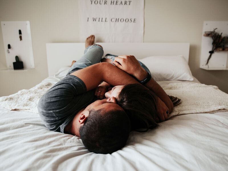 Couple lying arm in arm in big bed