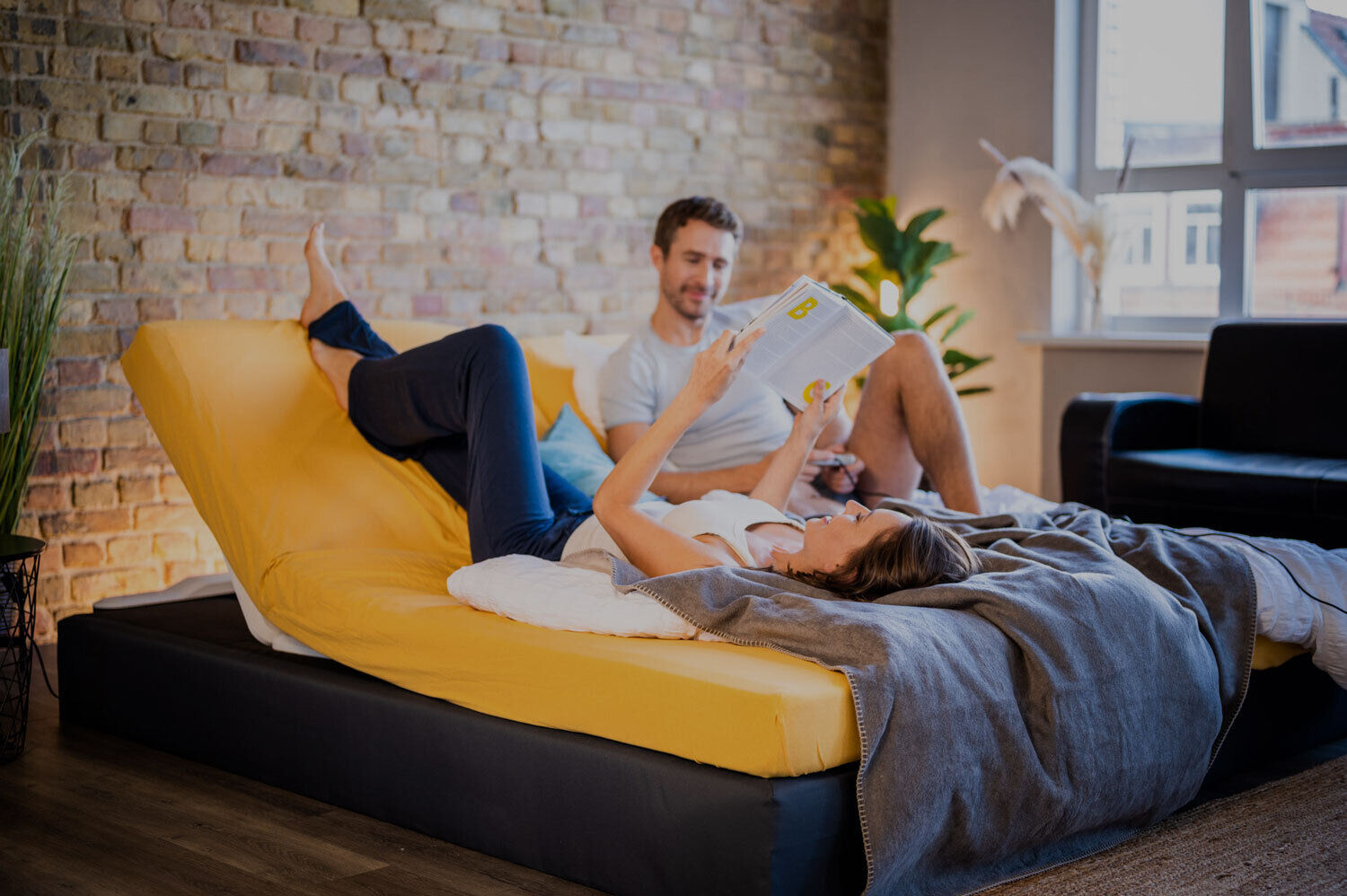 Woman and man lie in a large box spring bed with angled CosyLift