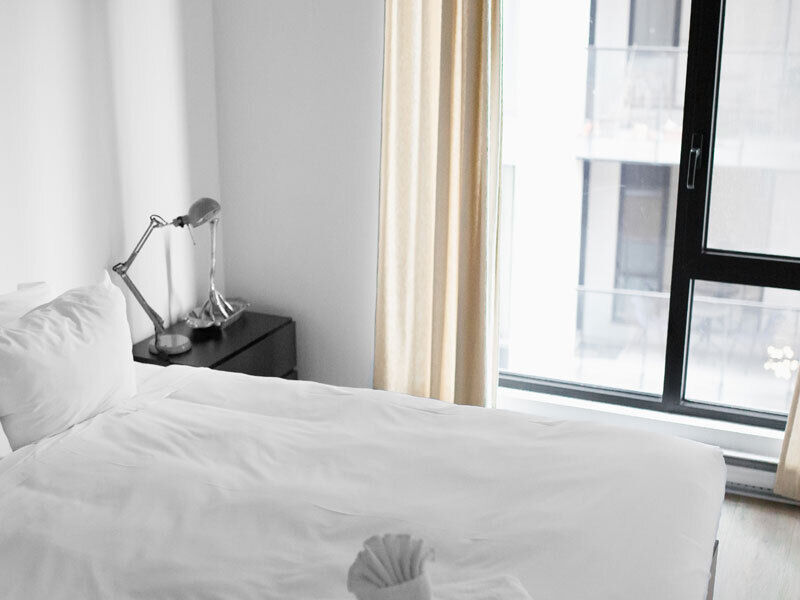 A made up bed with white bedding in a neat room