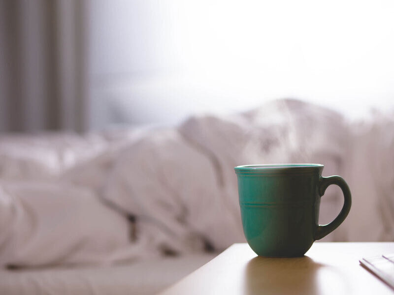 Grüne Tasse, die auf dem Nachttisch neben dem Bett steht