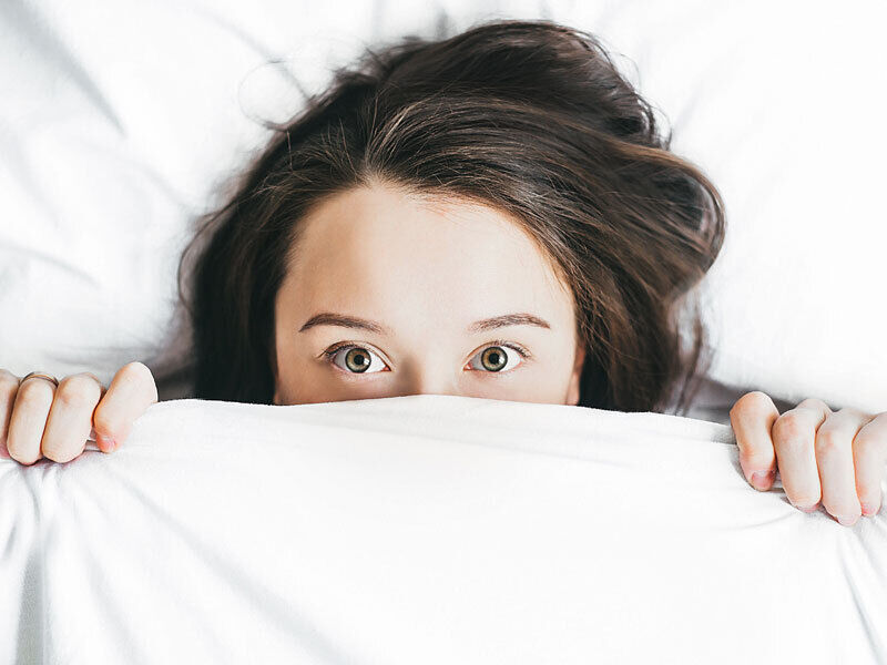 Girl half face curiously looking out of blanket