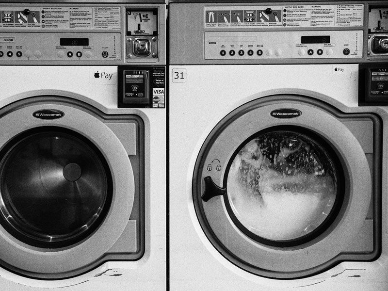 Zwei Waschmachinen, die eng nebeneinander stehen, von der eine Waschmachine Wäsche wäscht